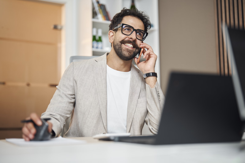 ERGO Mitarbeiter lachend am Telefon am Arbeitsplatz